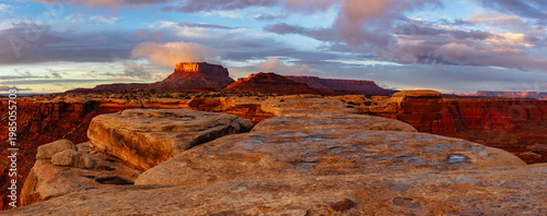 This scenic sunset panorama of Canyonlands National Park features White Crack with Junction Butte and the Island in the Sky rising above underneath a colorful sky.