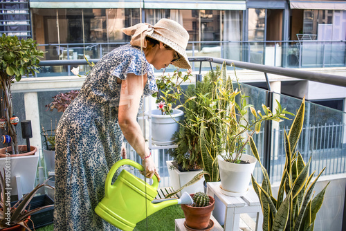 Mature Woman watering plants on balcony during home gardening