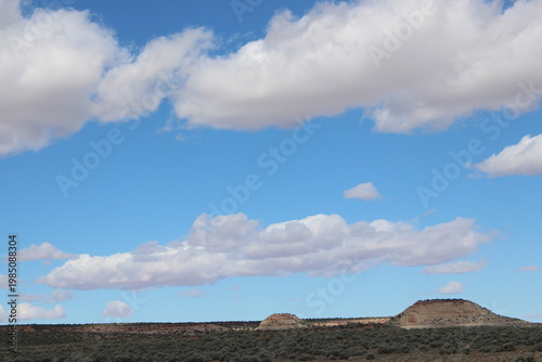 Photography Desert mesas and scrubland beneath large cumulus clouds in a bright blue sky in the American Southwest landscape