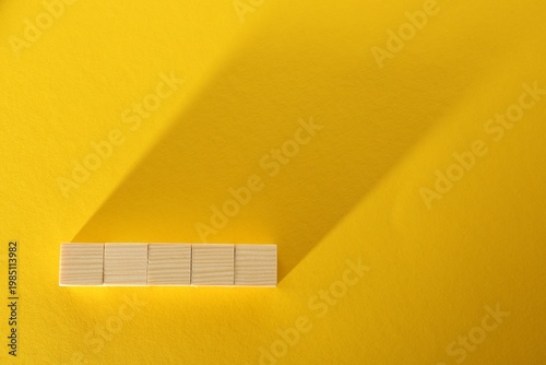 Blank wooden cubes on yellow background, flat lay. Space for text