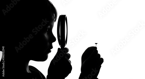 A silhouette of a child using a magnifying glass to examine an object
