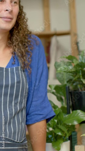 Vertical video: Panning worker in striped apron leaning on counter watching offscreen, copy space