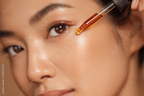 Beautiful Asian woman applying face serum with a dropper