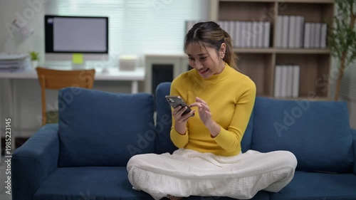 Woman Smiling While Using Smartphone on Sofa in Cozy Living Room