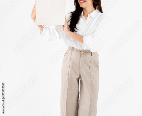 Asian woman body in white shirt and beige trousers holding plain gift box, isolated on white background