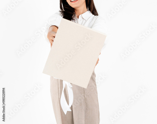 Asian woman body in white shirt and beige trousers holding plain gift box, isolated on white background