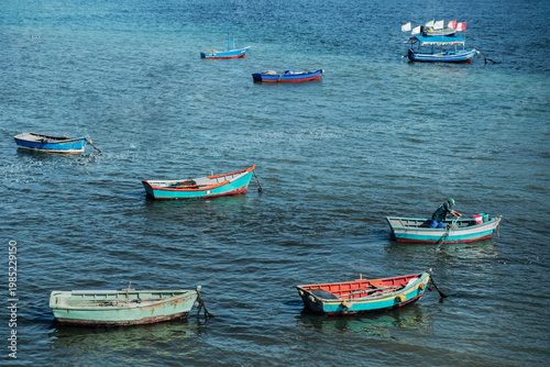 Schilderij op canvas Peruvian fisherman rowing boat among colorful vessels