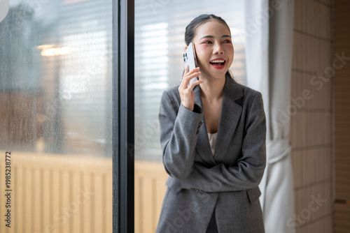 Schilderij op canvas Businesswoman smiling and talking on phone near rainy window