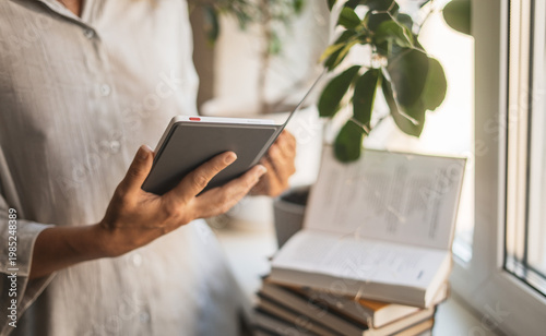Woman reading ebook in clean minimal space with natural decor. Concept of mindfulness, simplicity and distraction free environment supporting concentration, self education and mental wellbeing