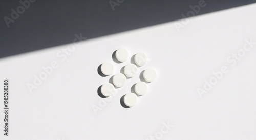White Round Pills Scattered on a White Background with Strong Shadows
