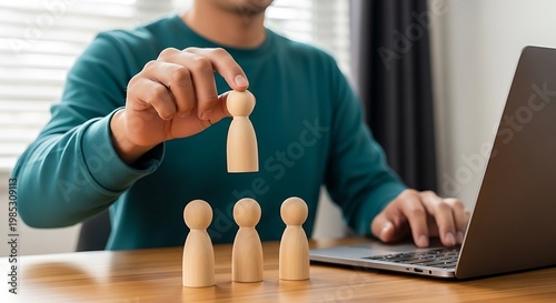 Businessman selecting individual wooden figure representing leadership and recruitment strategy at desk with laptop