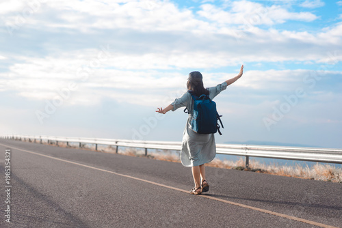 Rear view of young woman traveler with backpack freedom travel minimal background with blue sky