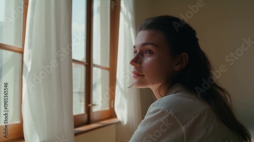 A Thoughtful Moment: A Young Woman Gazes Out the Window, Contemplating Life, Beauty, and Dreams in a Sunlit, Serene Room with Flowing Curtains