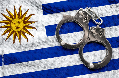 Flag of Uruguayi and police handcuffs. Crime and offenses in country Concept
