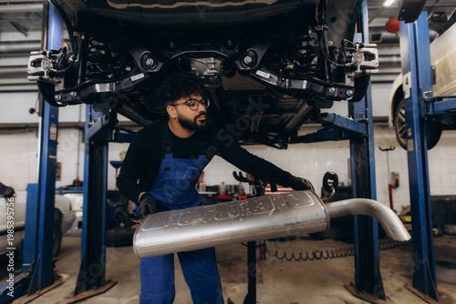 Foto Auto mechanic replacing car exhaust muffler in garage