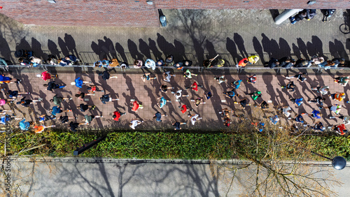 Aerial drone view of people running half marathon race in city, shadows of runners on road racing sport competition, top-down view of athletes and spectators, Venlo, the Netherlands