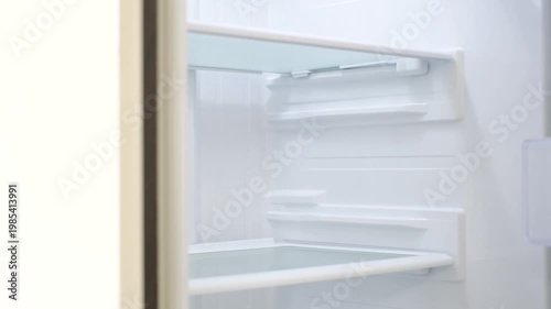 Modern open refrigerator close-up with empty shelves, side view.