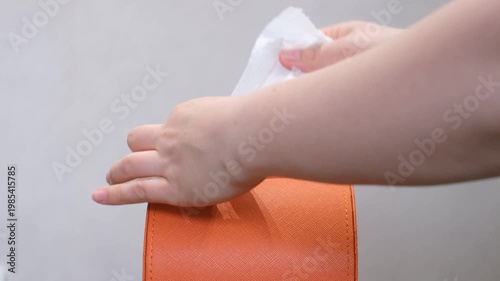 A hand pulls paper napkins out of orange box.