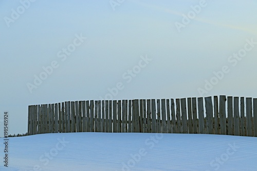 A wooden fence covered halfway with snow