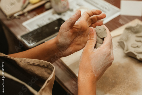 Hands gently molding clay at a ceramics art class, showcasing the tactile interaction with the material. The detailed process emphasizes creativity and craftsmanship in pottery-making.