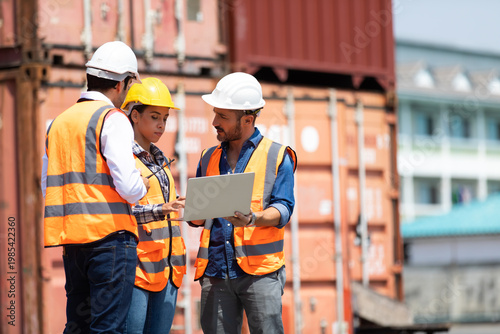 Hispanic man harbor worker talking on the walkie-talkie radio and control loading containers at container warehouse. container yard port of import and export goods