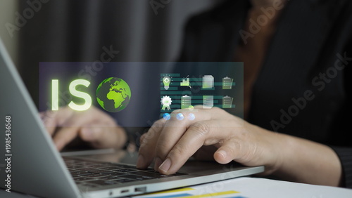 business professional working on a laptop with a virtual ISO certification interface, displaying a green globe and quality management icons for corporate standards and global compliance.