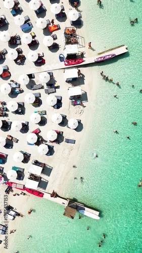 Aerial view of beachgoers swimming and relaxing on sandy shore  