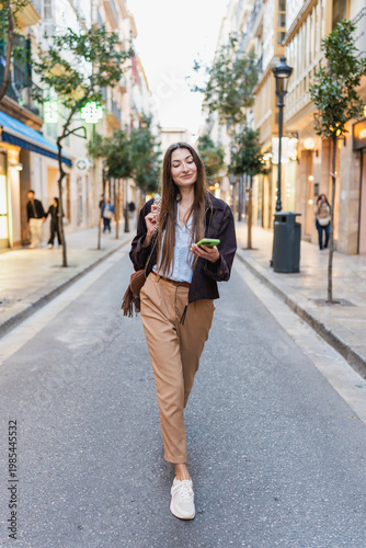 Young woman walking city street using phone