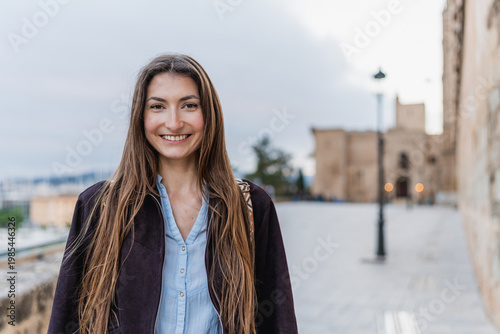 Young woman smiling outdoors, looking at camera