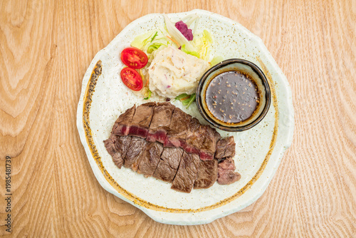 Sliced beef steak with salad and sauce