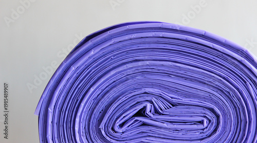 Roll of violet biodegradable plastic bags for home garbage on a white background
