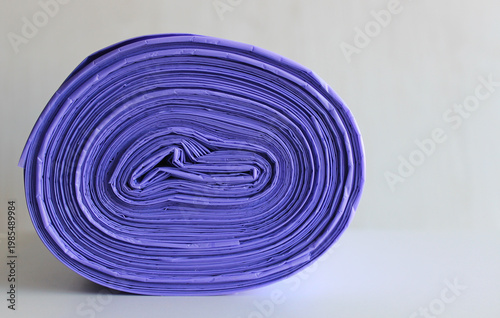 Rolled Disposable Waste Bags Made With Violet Polyethylene On White Surface 
