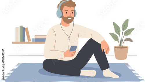 A man relaxes on a rug wearing headphones and listening to music on his phone.