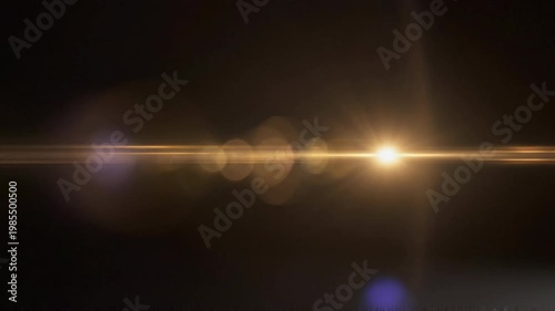 Elegant lens flare on black backdrop concept. Bright golden light flare effect with glowing bokeh highlights on dark background for creative design