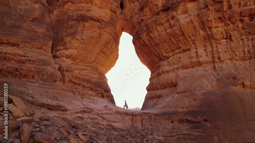 Discovering AlUla in Saudi Arabia, walking on the rock. Landscape with huge sandstone rocks of Arabic Peninsula, woman tourist climbing