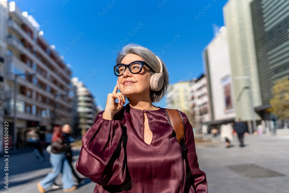 Fototapeta premium Mature woman listening to music enjoying urban environment