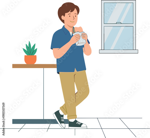 A man stands indoors drinking a beverage from a bottle near a table.