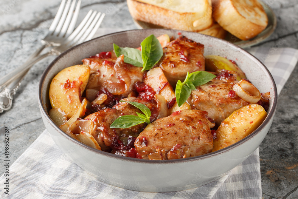 Fototapeta premium Roasted pork tenderloin with caramelized onions, cranberry sauce and green apples close-up in a bowl on the table. Horizontal