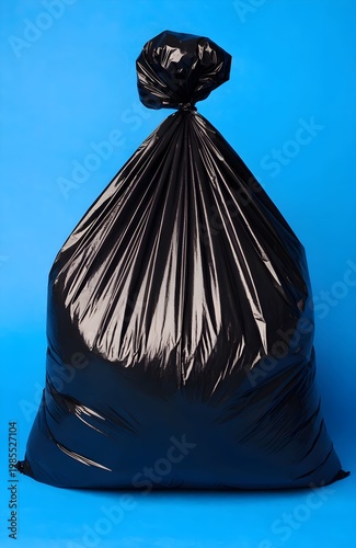 Glossy black garbage bag tied at the top against a vivid blue background, symbolizing waste management, recycling awareness, and urban cleanliness in modern society