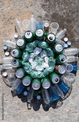 Circular arrangement of discarded cans, bottles, cups, and paper on concrete surface, symbolizing recycling, pollution awareness, sustainability, and environmental responsibility