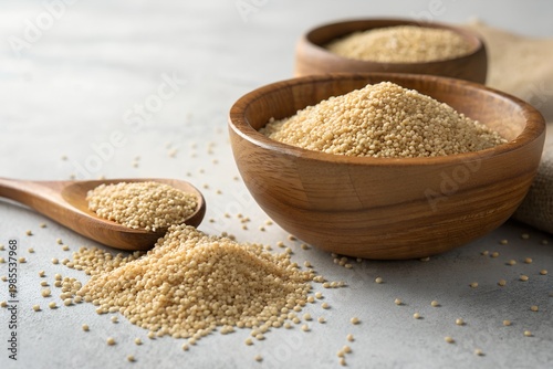 Amaranth Month A wooden bowl filled with sesame seeds next to a spoon on a gray surface