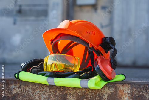 Foto Professional safety gear with helmet with hearing protection eye shields and reflective vest on a rusty metal surface