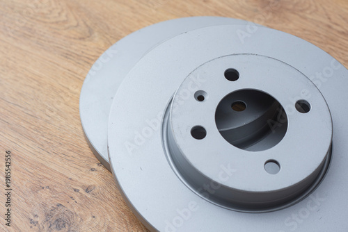 Photography Pair of brand new ventilated metal brake rotors placed on a wood surface