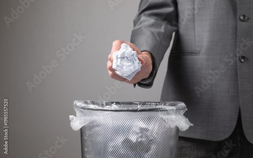 Foto Man throwing crumpled paper into rubbish bin.