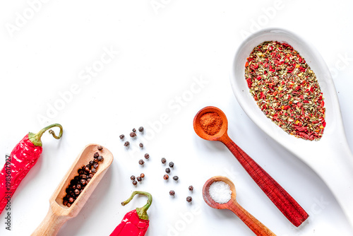 spices in wooden spoon on white background top view