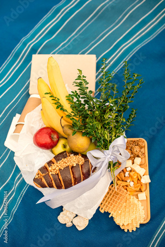 flat lay set for picnic or breakfast with fruit and croissant on blue blanket outdoors