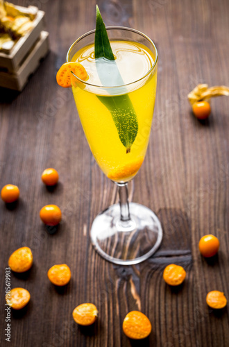 cocktail with physalis in glass on wooden background