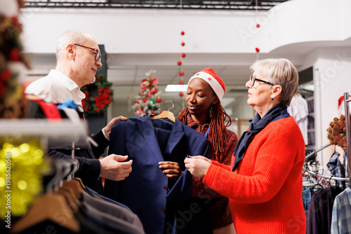 Foto Employee presenting clothes to clients, describing fabric for senior customers on christmas shopping spree