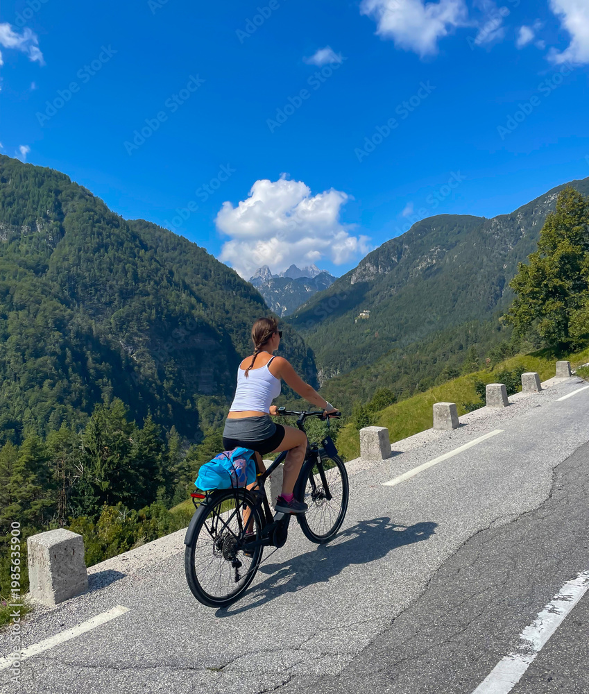 Fototapeta premium VERTICAL: Female traveler exploring the Soca valley and mountains on an ebike.