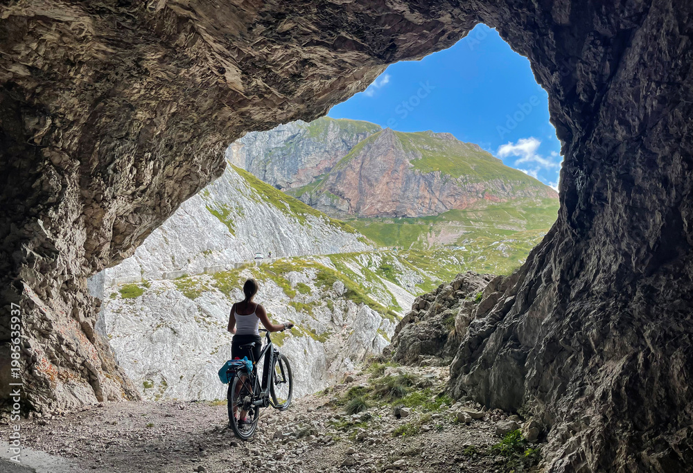 Fototapeta premium Young woman cycling in the Slovenian mountains stops at a scenic viewpoint.